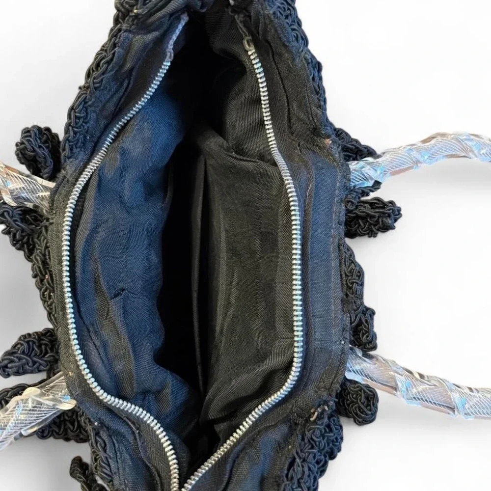 Black crocheted corde handbag featuring a clear, twisted Lucite handle